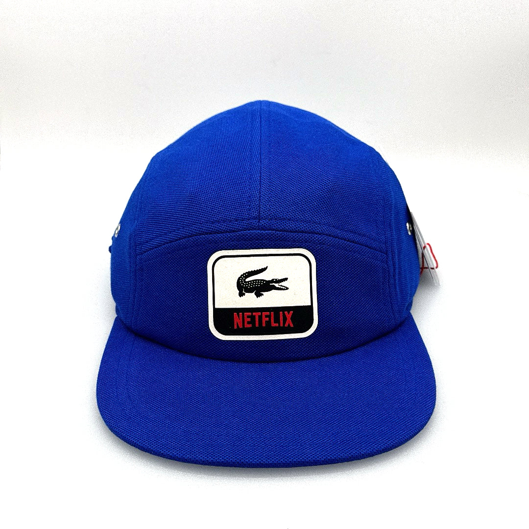 Blue Netflix Lacoste 5 Panel Hat, white alligator along with Netflix logo on the front, with white background.