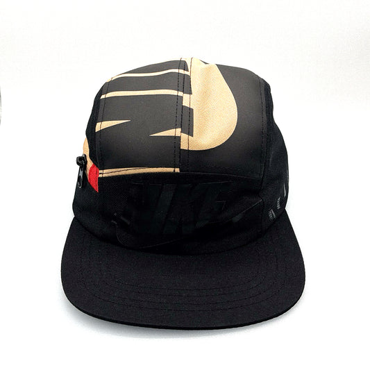 Black and tan NIKE shoe box bag upcycled to a 5 Panel Hat, zipper on right side panel, with white background.