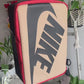 The making of a black and tan NIKE shoe box bag upcycled to a 5 Panel Hat, zipper on right side panel, with white background.