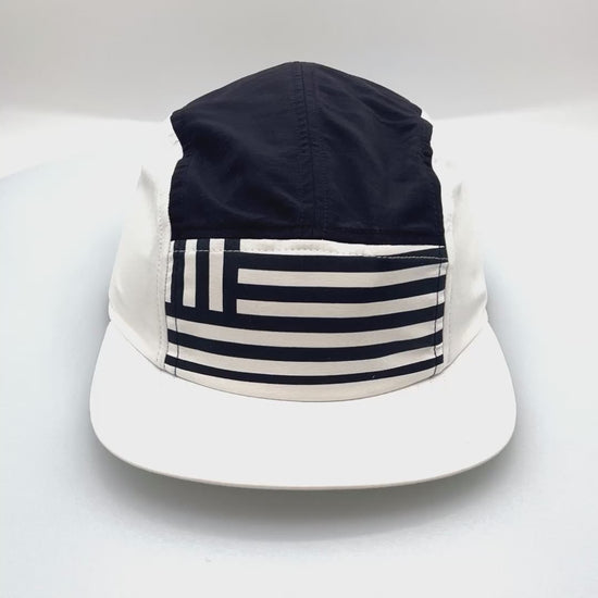 Spinning navy and white North Face 5 Panel Hat, flag print on the front, with a white background.