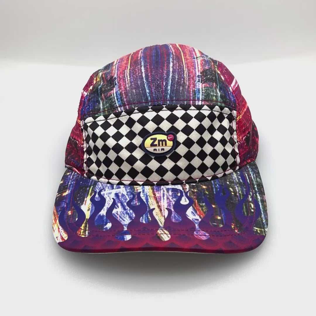 Spinning multi colored flame NIKE ZM Air 5 Panel Hat, rubber NIKE logo on front, with a white background.