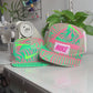 The making of a fluorescent green and pink Nike sweatshirt fleece upcycled into a 5 Panel Hat, Nike logos throughout, with a white background.