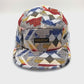 Spinning grey and black Staple Standard Pigeon 5 Panel Hat, with a white background.