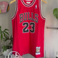 The making of a red and white upcycled MJ jersey made into a 5 Panel Hat, BULLS stitched on the top panel, white background.